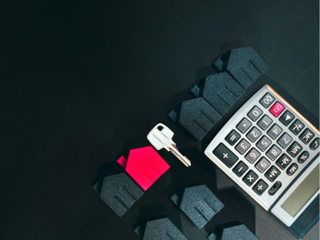 House keys and a calculator beside model houses, representing rental property management in Malaysia